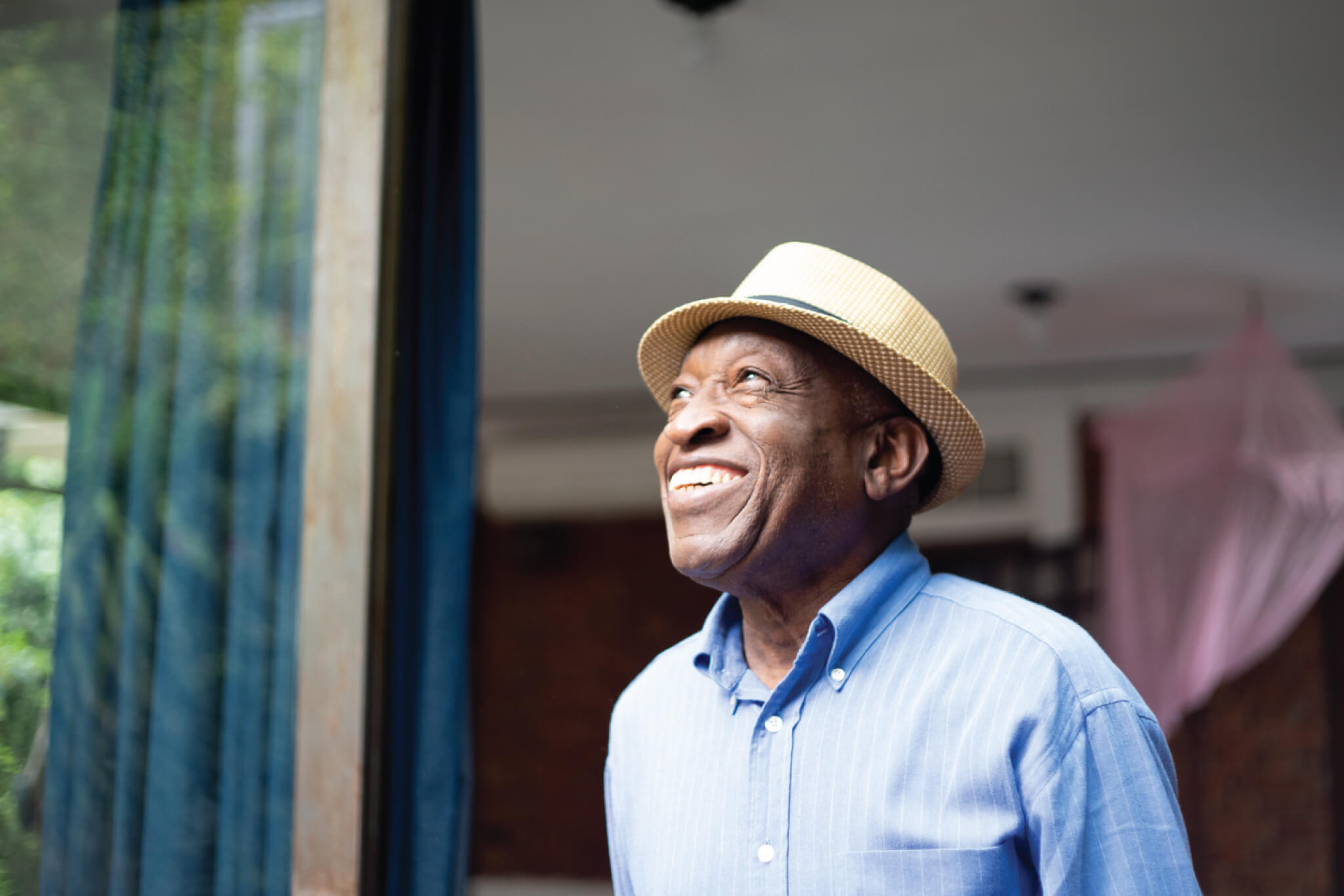 Senior man wearing hat while looking out the window