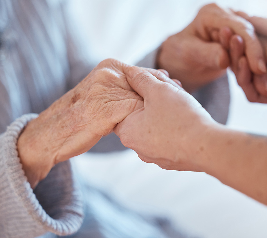 Caregiver holding hands with a senior individual, offering comfort and support.