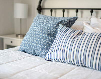 Close-up of a neatly made bed with two blue decorative pillows in an elegant unit.