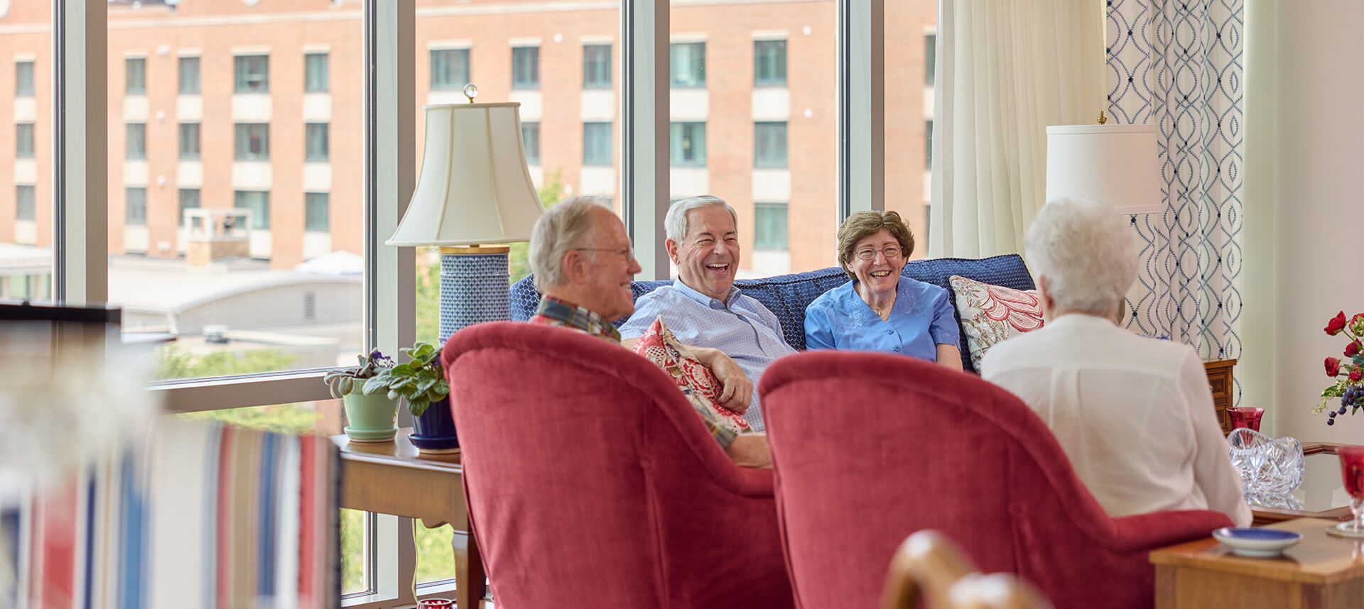 Group of seniors enjoying social time in a well-lit common area of a senior living unit.