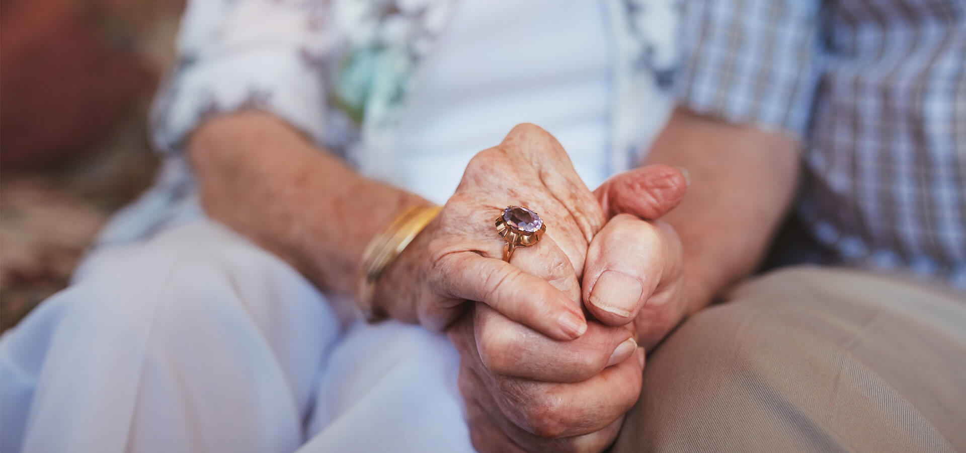 senior couple sit together and hold hands